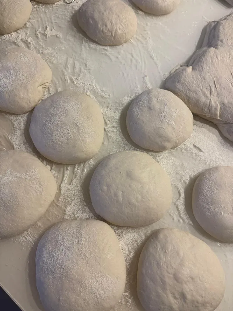 Rounded balls of sourdough dough resting on a floured bench