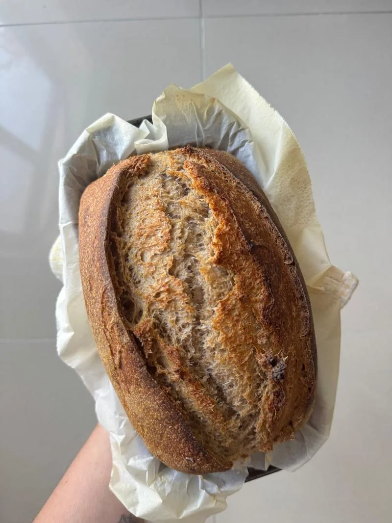 Crusty wholemeal sourdough loaf in baking paper